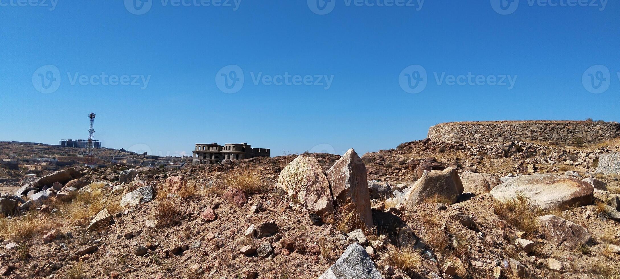 a rocky hill with a large rock and a tower photo