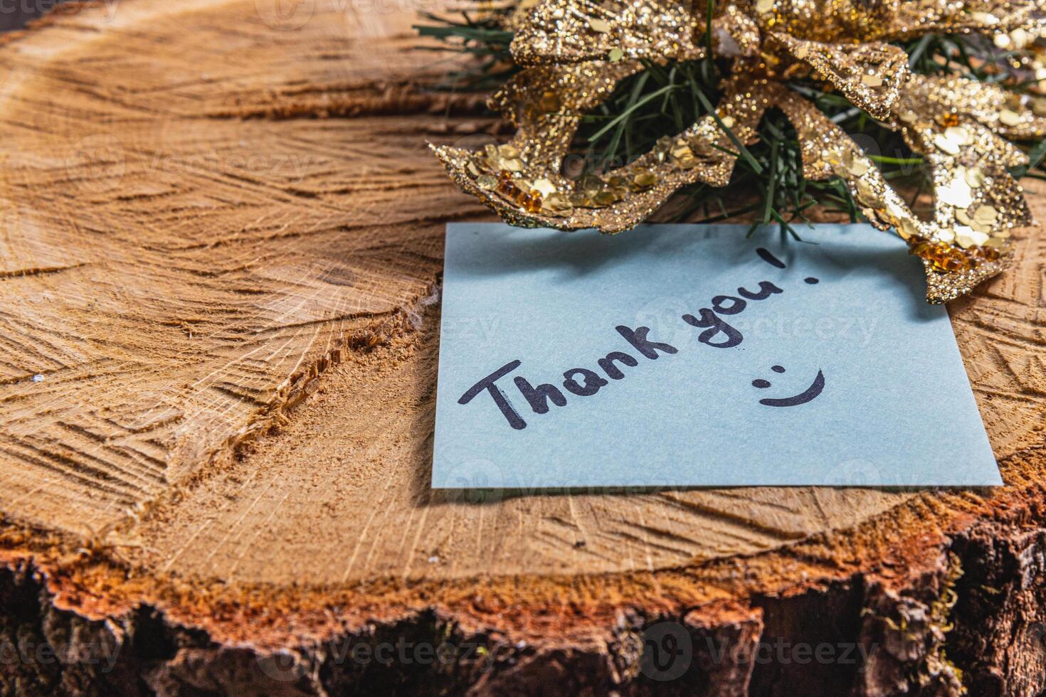 The word thank you for the light of a blue leaf on a piece of wood photo