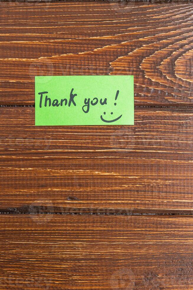 A small green note with the word thank you on a turf table photo