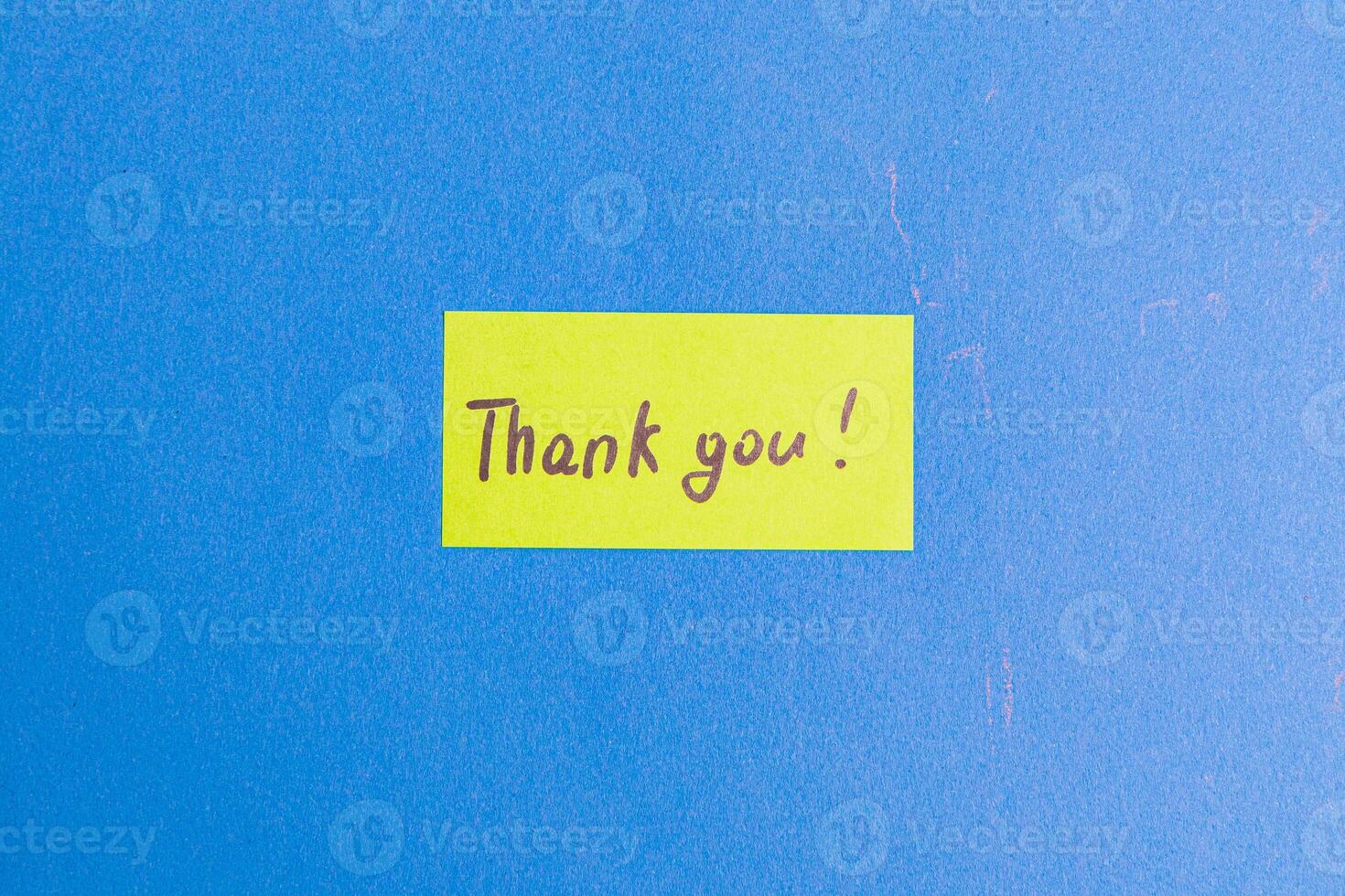 A small yellow note with the word thank you on a blue background photo