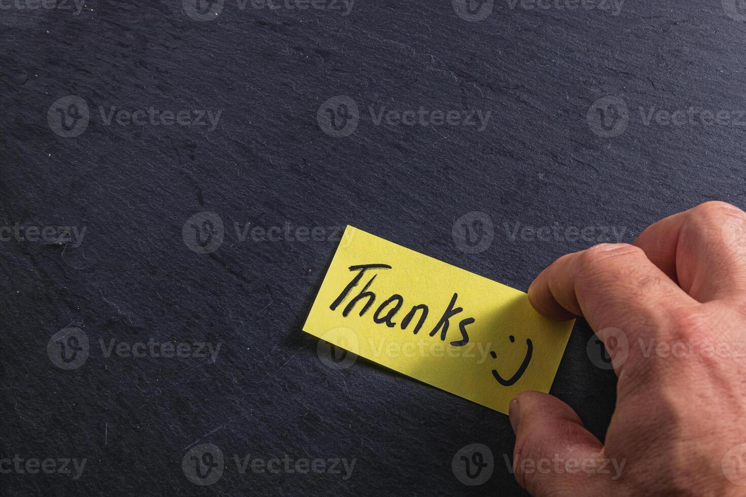 The man is holding a piece of paper with the word thank you in his right hand photo