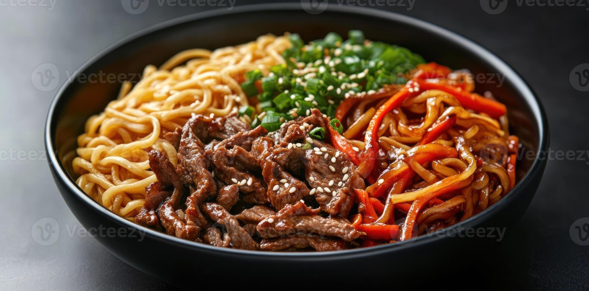 Close-up of Beef Stir-fry with Noodles and Vegetables in a Black Bowl photo