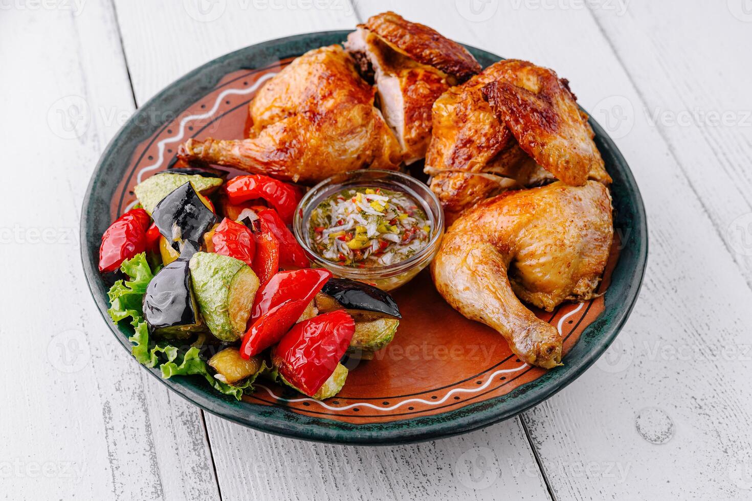 Roasted chicken with vegetables and sauce on rustic plate photo