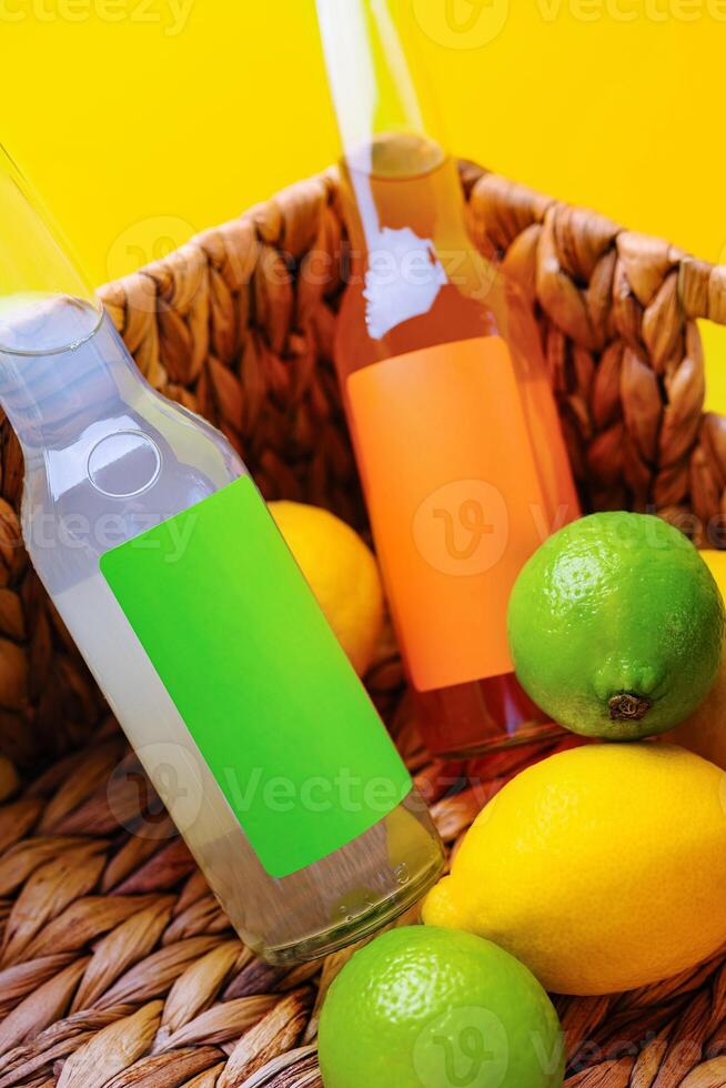 Two bottles resting in basket with lemons and limes on yellow background photo