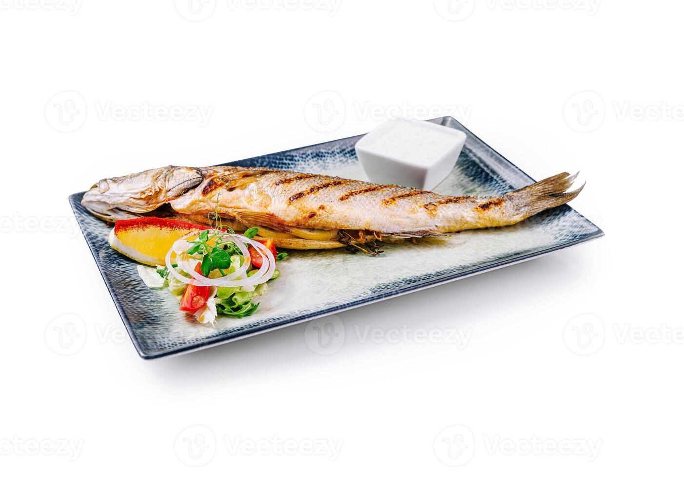 Grilled sea bass served on a plate with salad and sauce photo