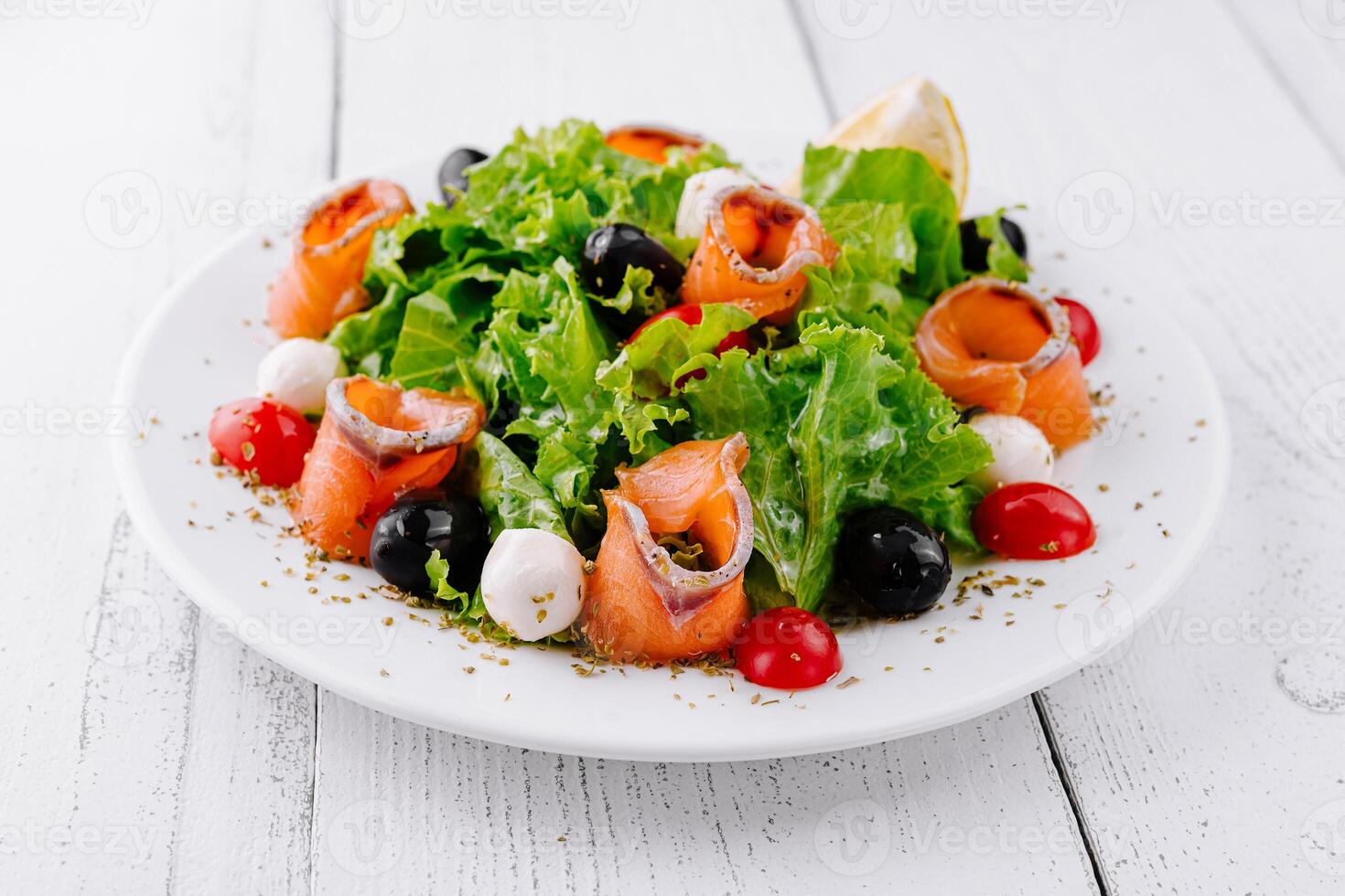 Delicious salad with smoked salmon, mozzarella and cherry tomatoes on white table photo