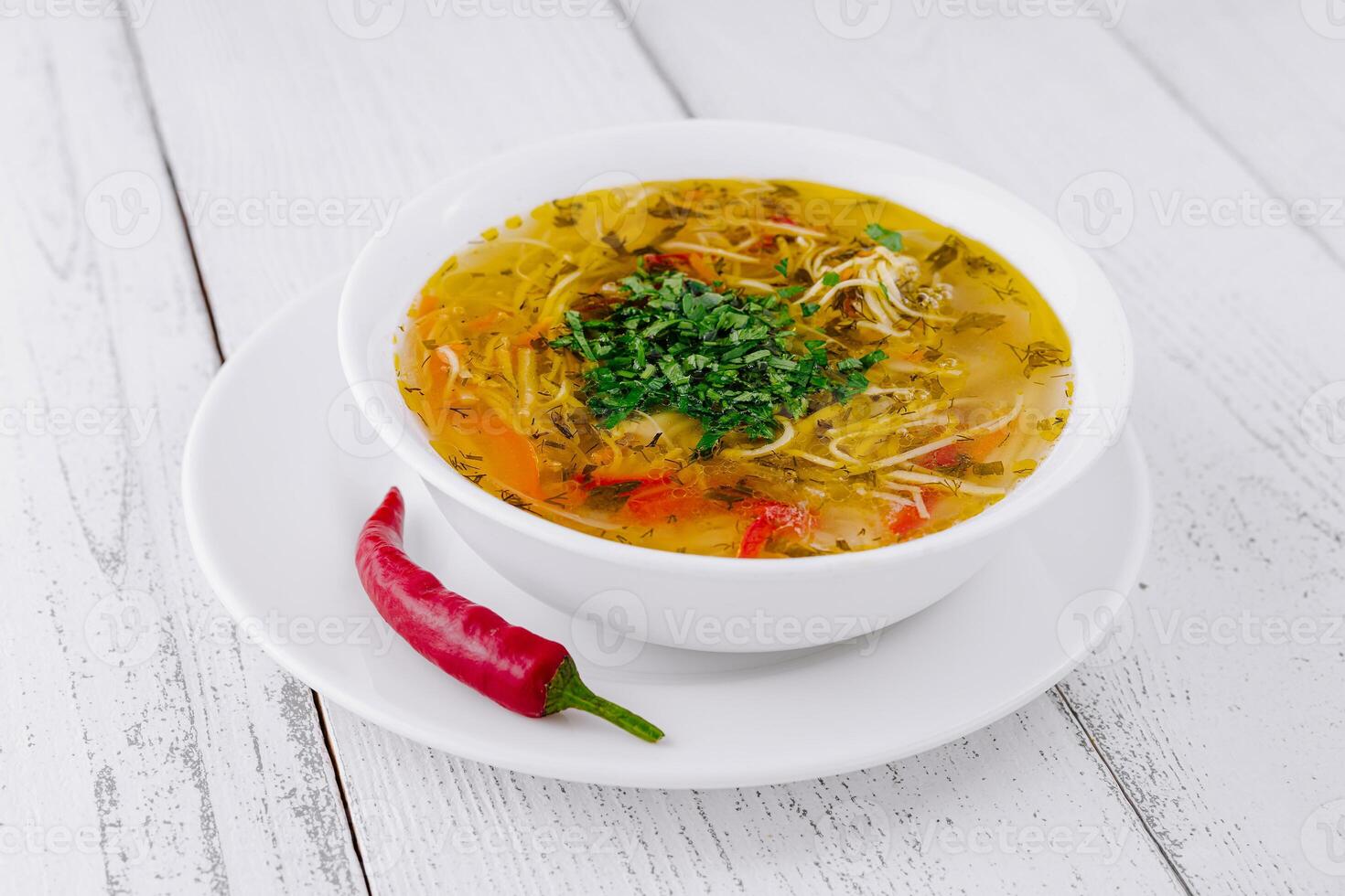 Steaming hot bowl of chicken noodle soup with herbs and spices photo