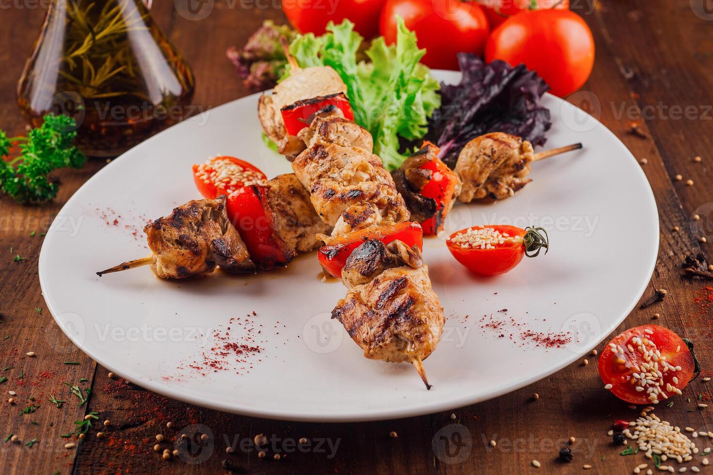 Grilled chicken and bell pepper skewers with cherry tomatoes and spices on a white plate photo