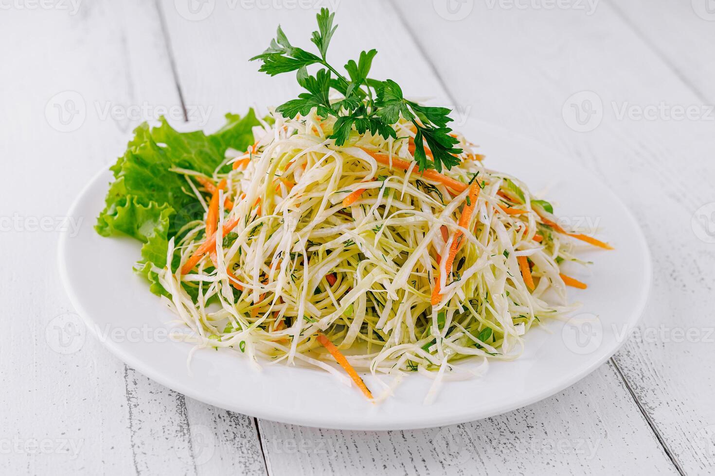 Fresh cabbage salad with carrots and greens on white plate photo