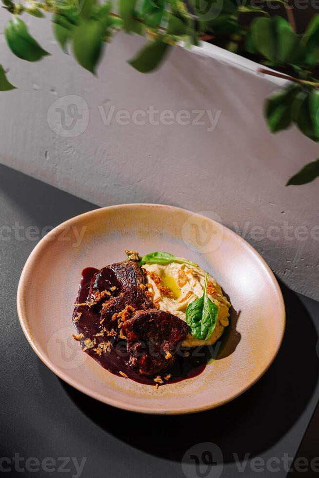 Gourmet beef cheeks with creamy polenta and red wine sauce being served on elegant plate photo