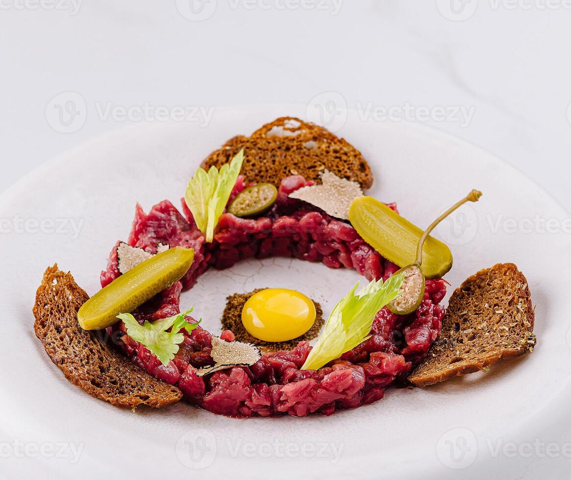 Deconstructed beef tartare with quail egg and rye bread photo
