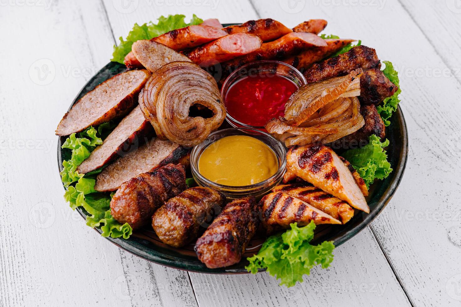 Grilled meat platter with sausages, chicken, and kebabs with dipping sauces photo