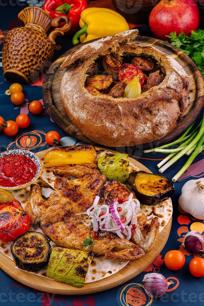 Traditional georgian cuisine with grilled chicken, vegetables and baked bread on table photo
