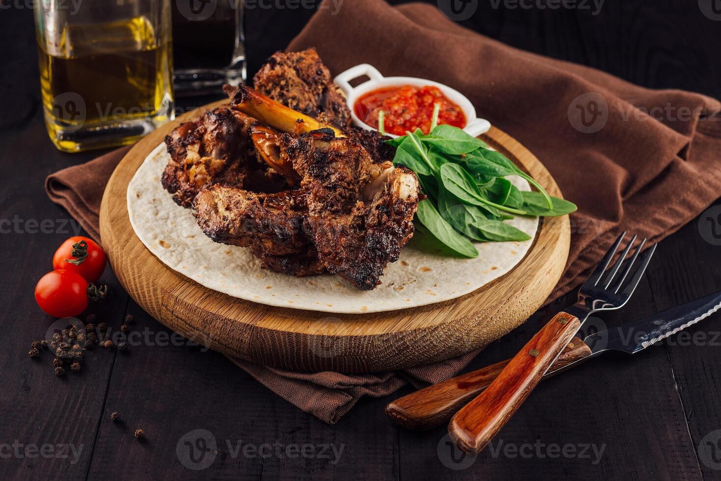Grilled lamb ribs served on tortilla with spinach and sauce on wooden board photo
