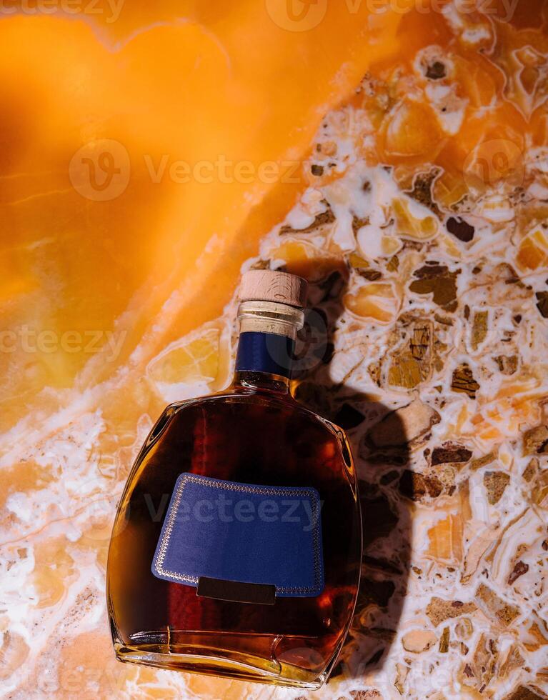 Bottle of brandy resting on an onyx surface photo