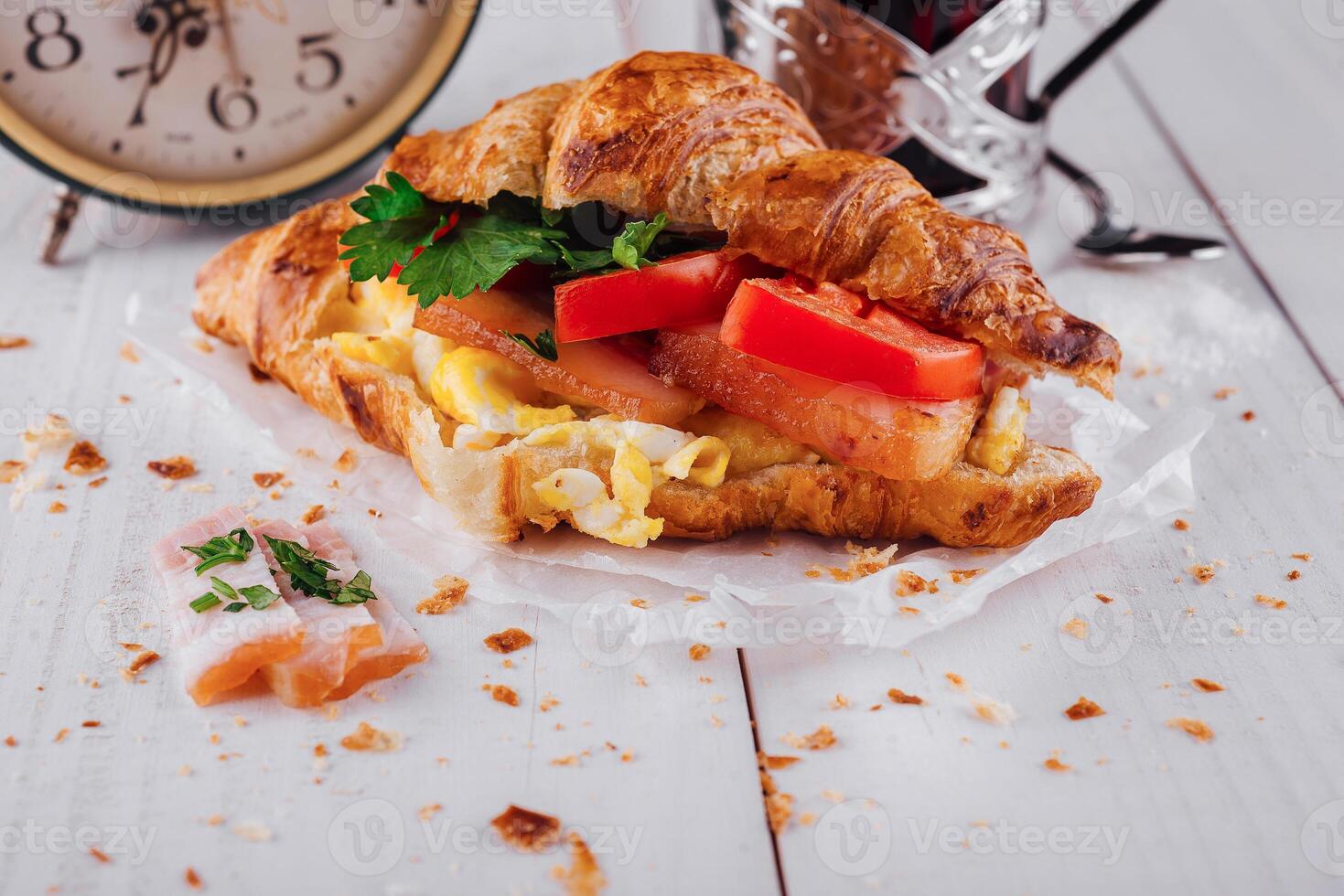 Delicious croissant filled with ham, scrambled eggs and tomato for breakfast photo