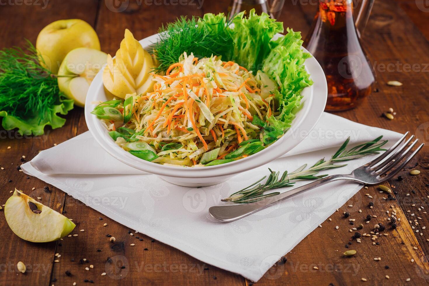 Fresh cabbage salad with apple slices and herbs on wooden table photo
