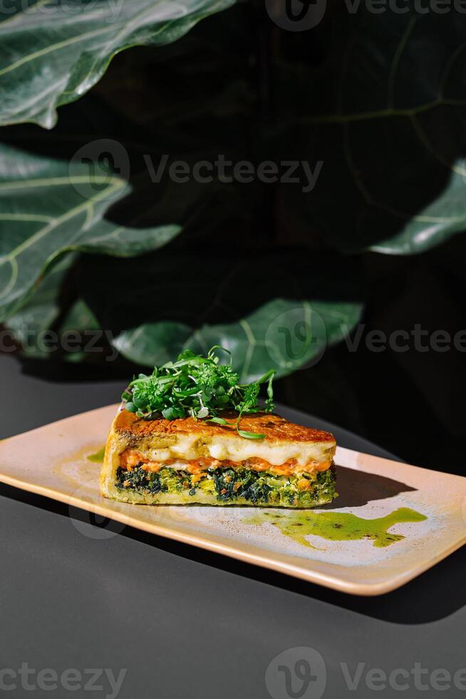 Delicious slice of quiche with salmon and spinach resting on plate photo