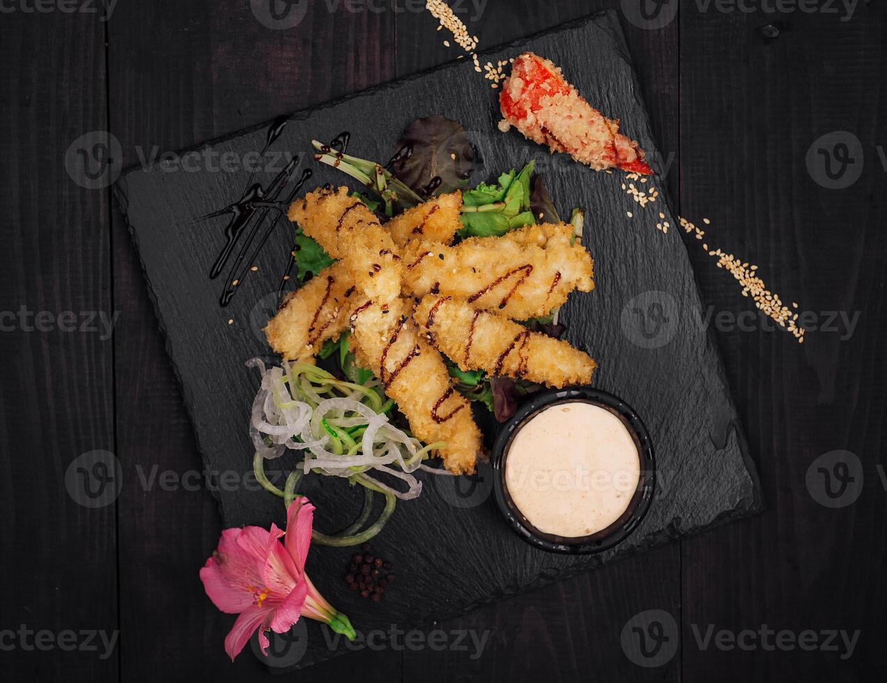 Delicious tempura shrimps being served on black stone plate photo
