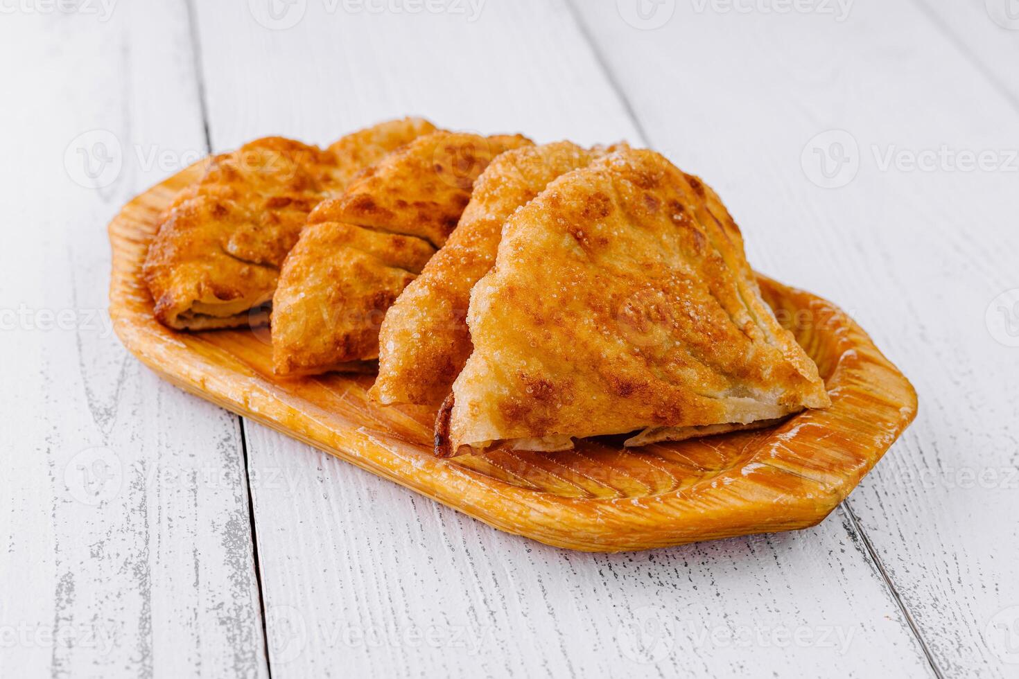 Delicious chebureki pastries resting on a wooden plate photo