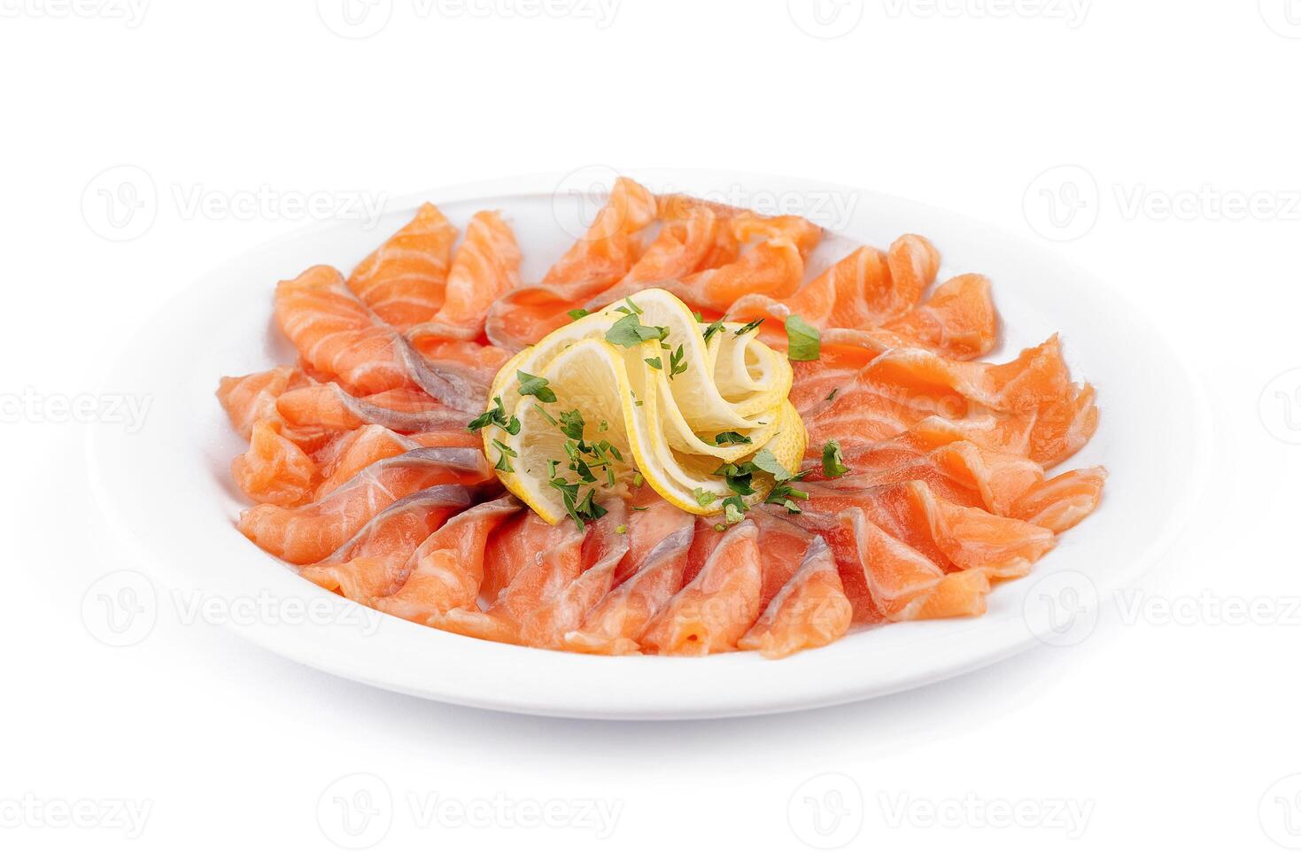 Sliced salmon fillet decorated with lemon and parsley on white plate photo