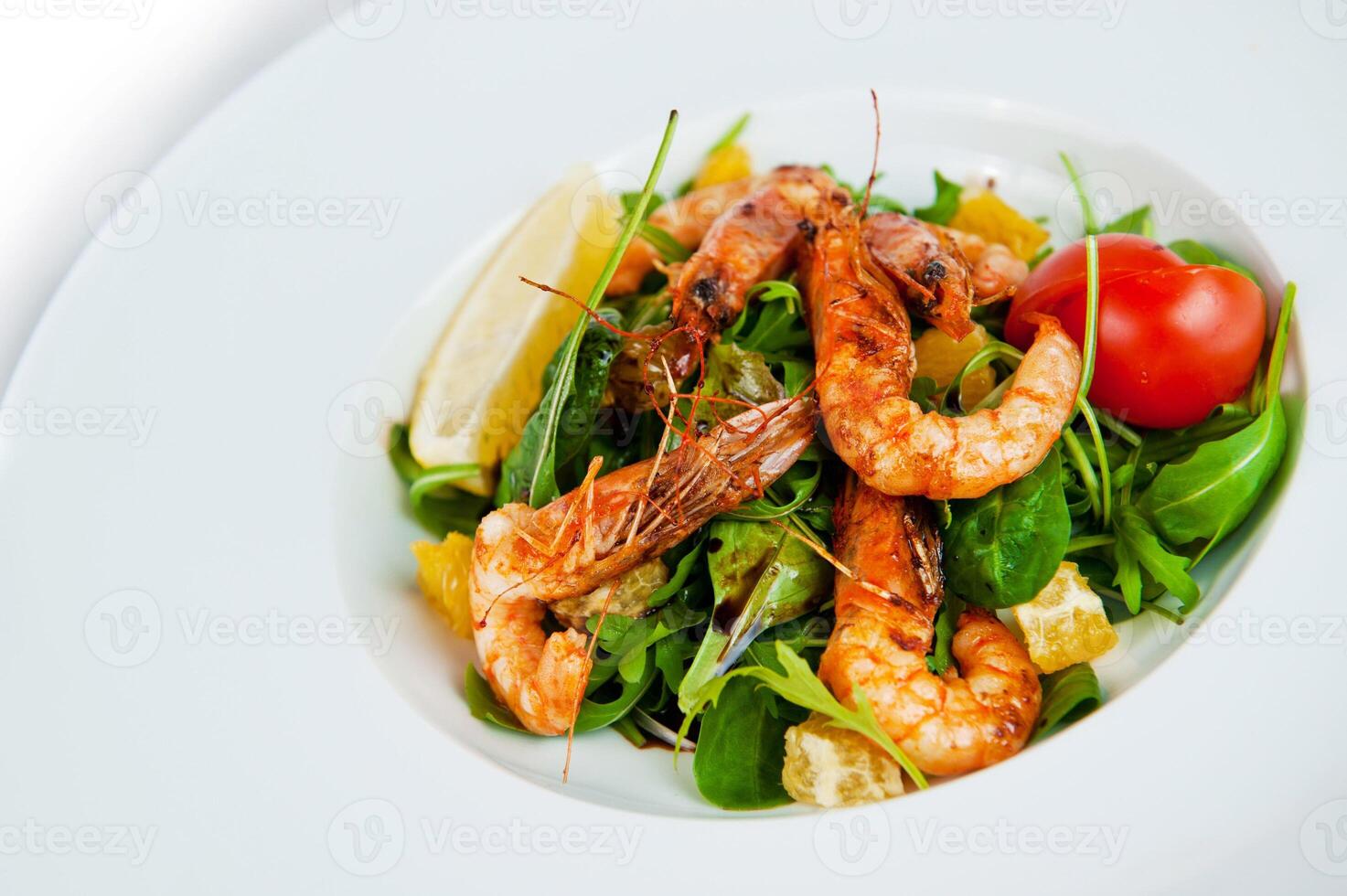 Delicious salad with grilled shrimps, arugula and orange slices on white plate photo