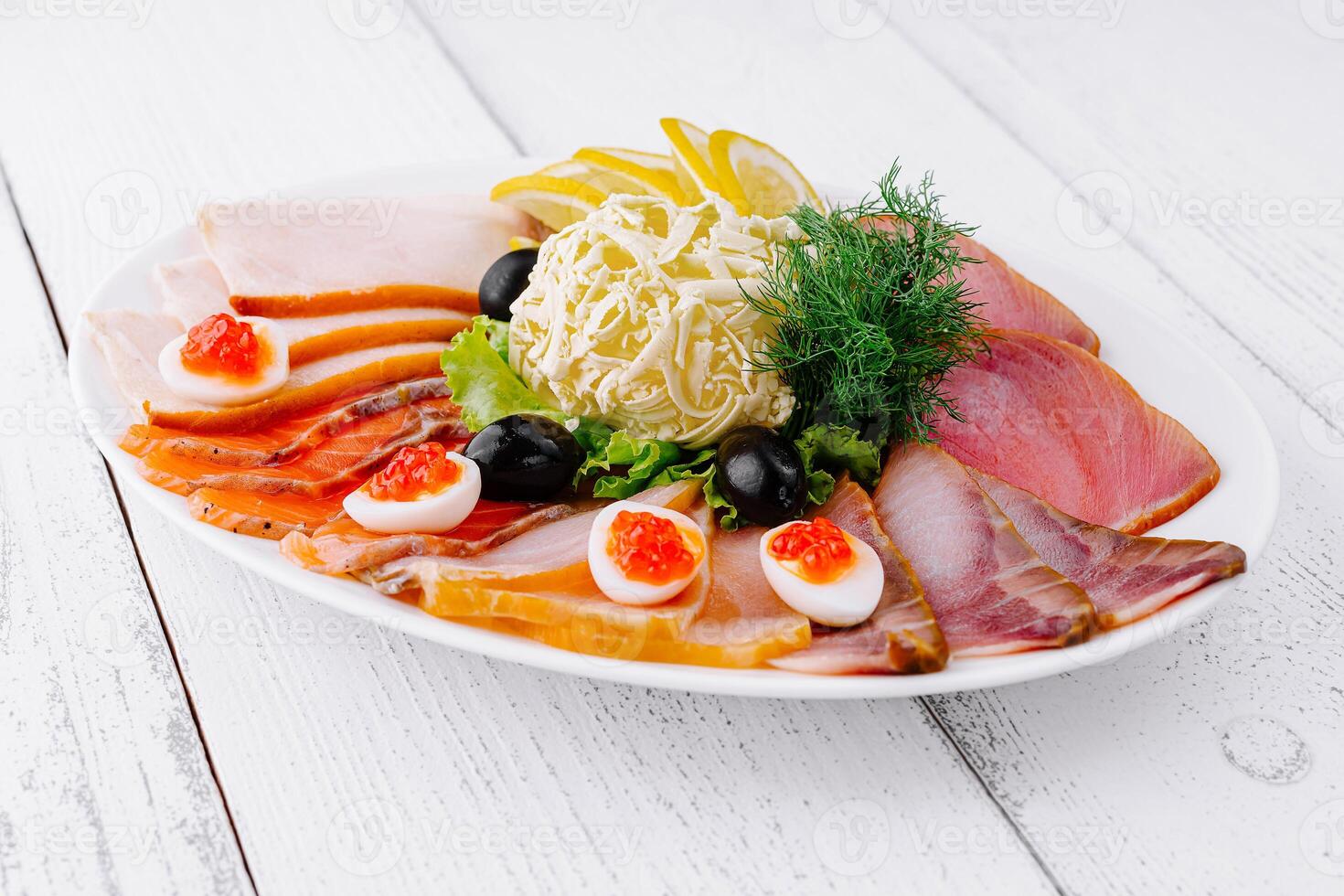 Delicious sliced fish platter with butter lemon and olives on white table photo