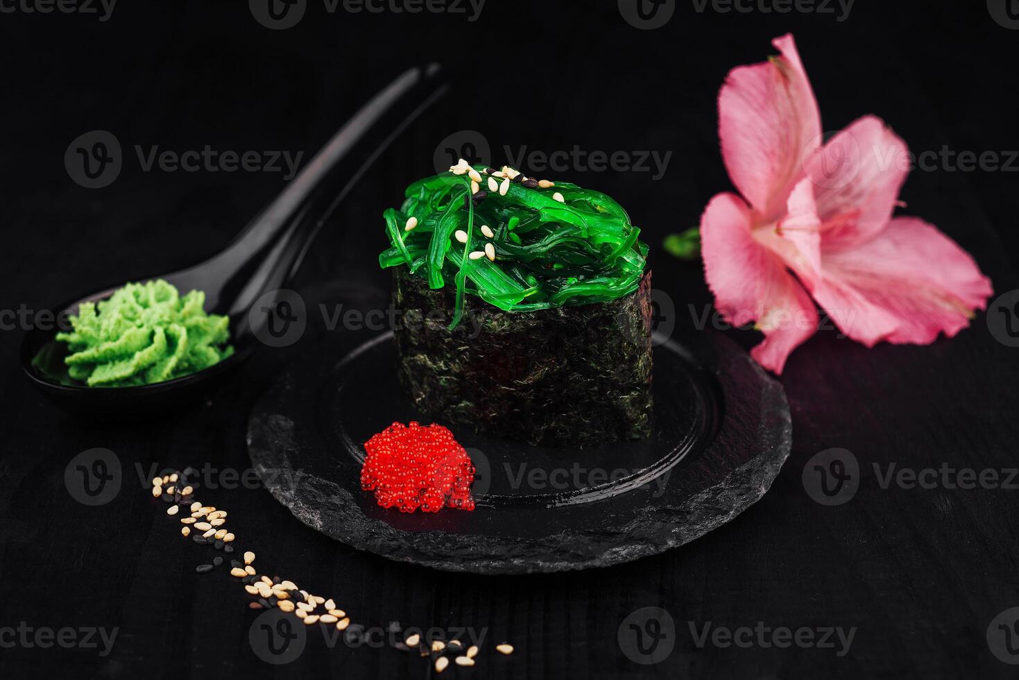 Gunkan maki sushi with green seaweed and sesame seeds on black background photo