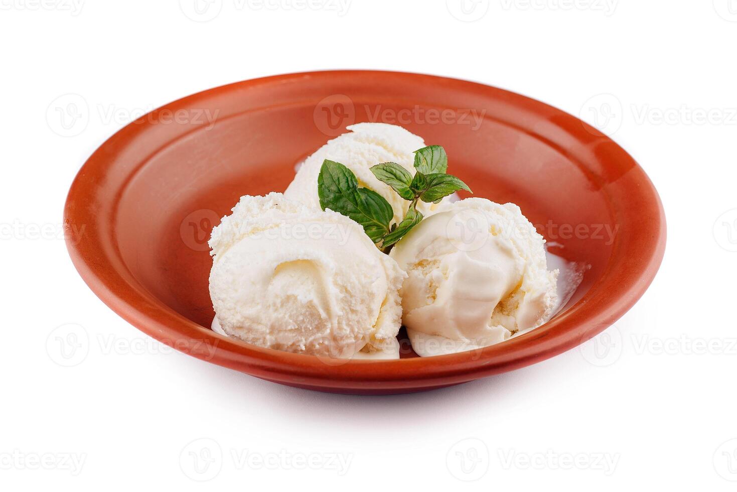 Three scoops of vanilla ice cream melting in rustic bowl with mint garnish photo