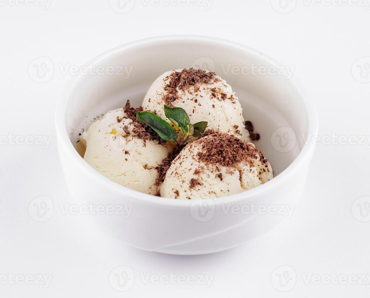 White bowl with vanilla ice cream decorated with chocolate shavings and mint leaf on white background photo
