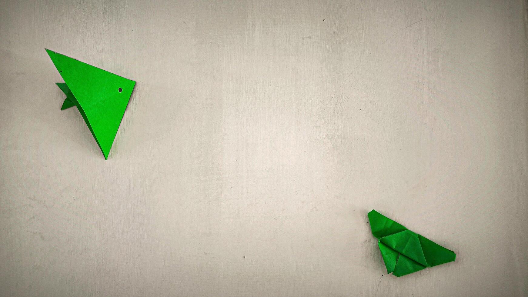 A green origami bird on a white wall photo