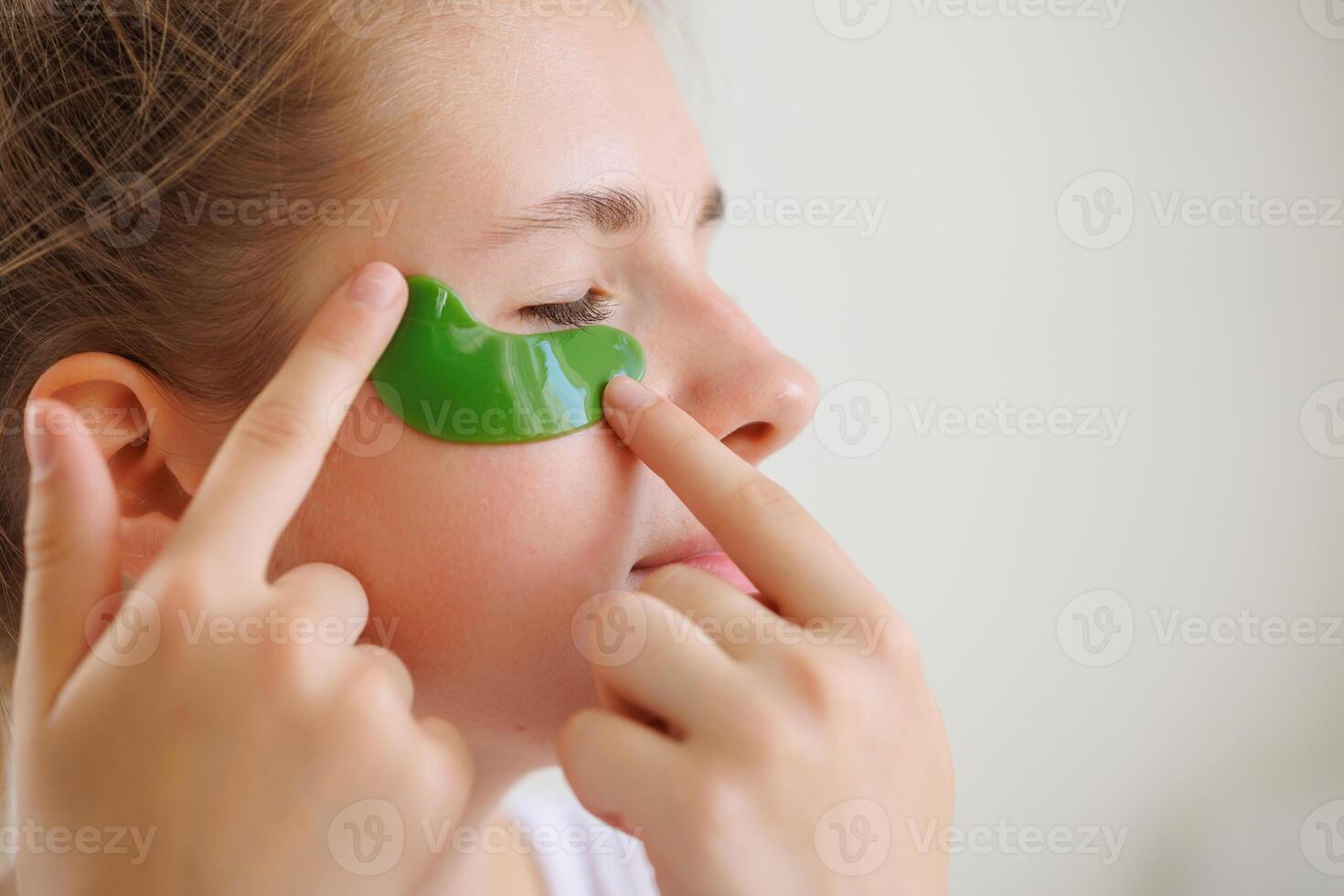 a girl applies moisturizing patches with vitamins under her eyes, a modern cosmetic product for the eyes to smooth out fine wrinkles and remove redness photo
