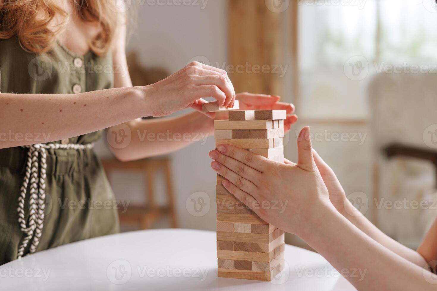two women playing a board game made of wooden blocks at home, excitement and relaxation, mind development concept, hand motor skills, photo