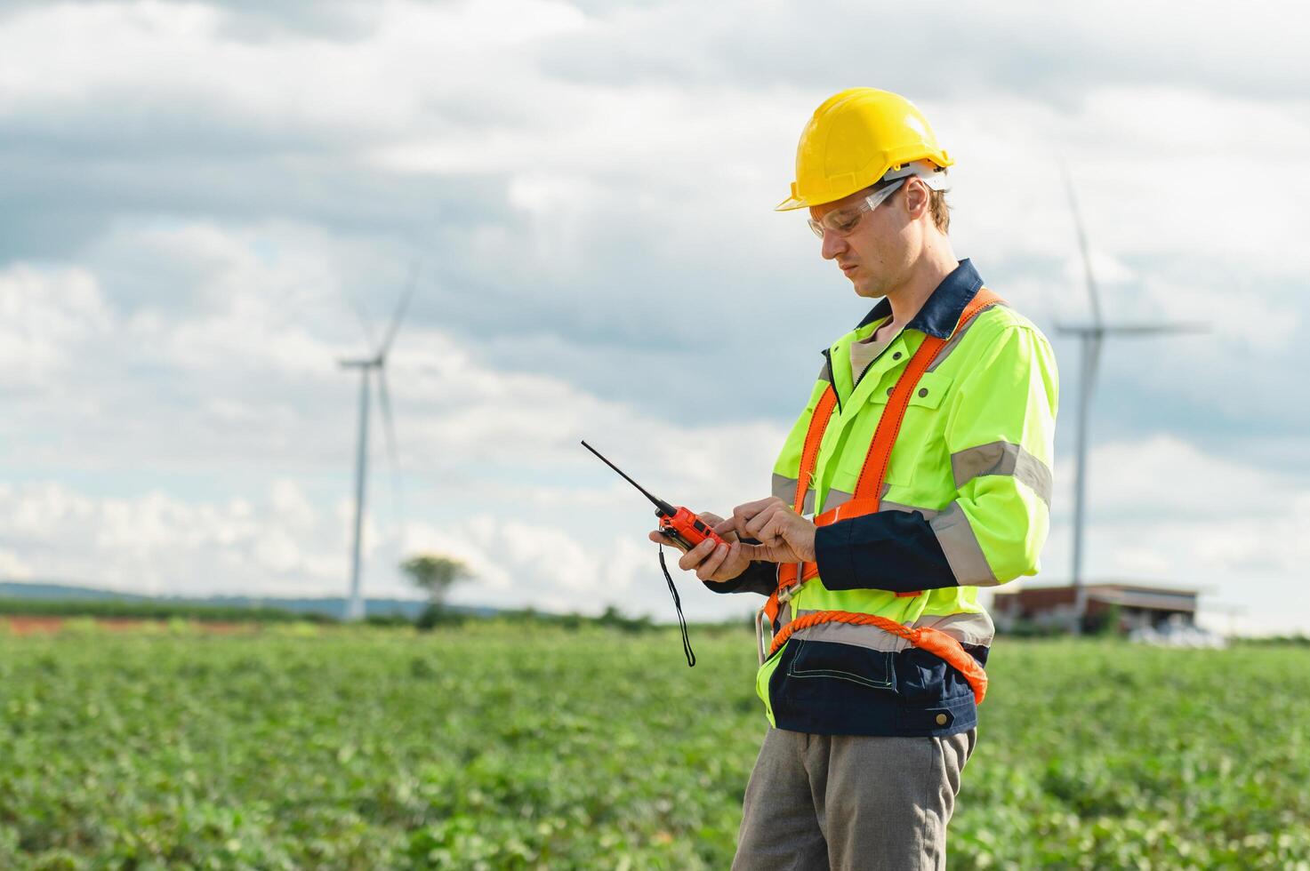 man in a yellow and orange safety vest is looking at a device photo