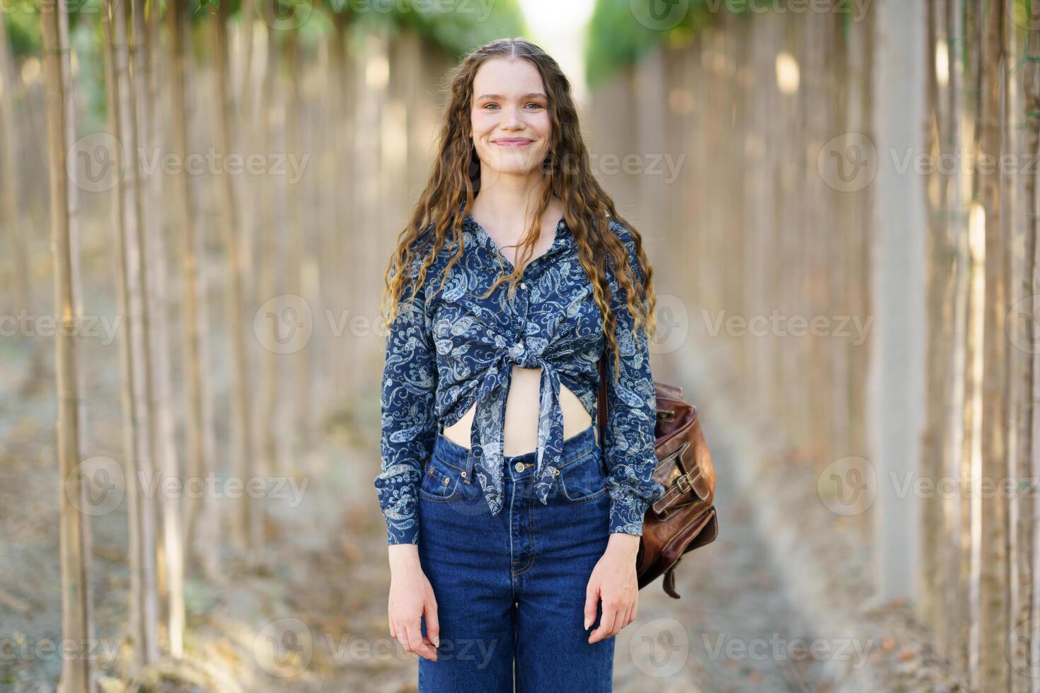 A Young Woman Dressed in a Beautiful Floral Top Walking Through Scenic Rows of Vines photo