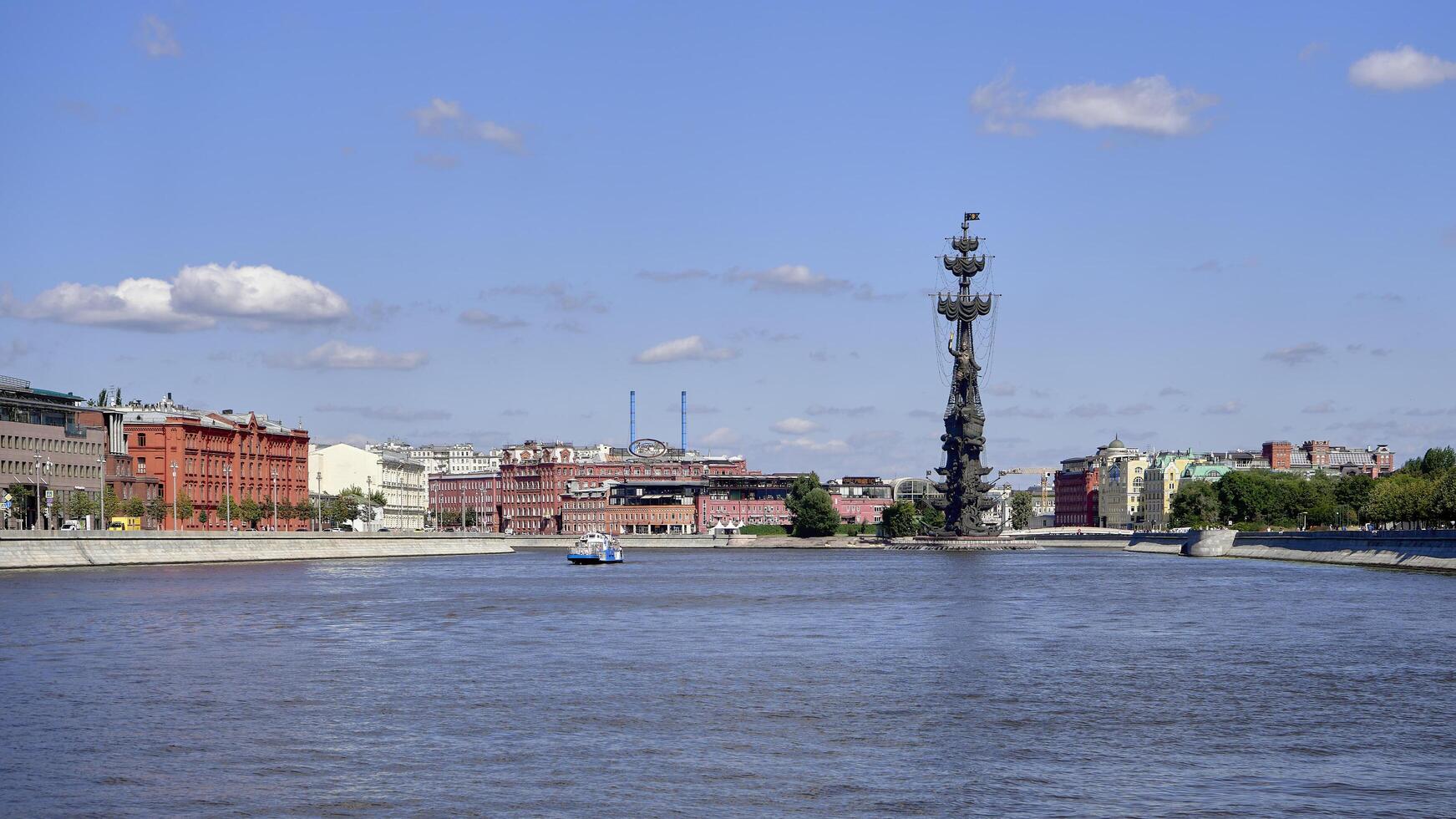 Moscow, Russia - July 25, 2022 Moscow river and Peter the Great Statue. Sculpture by Zurab Tsereteli. The Cathedral of Christ the Savior and the Confectionery factory Red October in background. photo