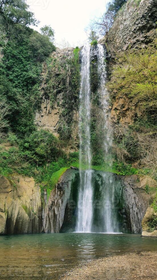 Beautiful waterfall cascading down a moss covered cliff face in springtime photo