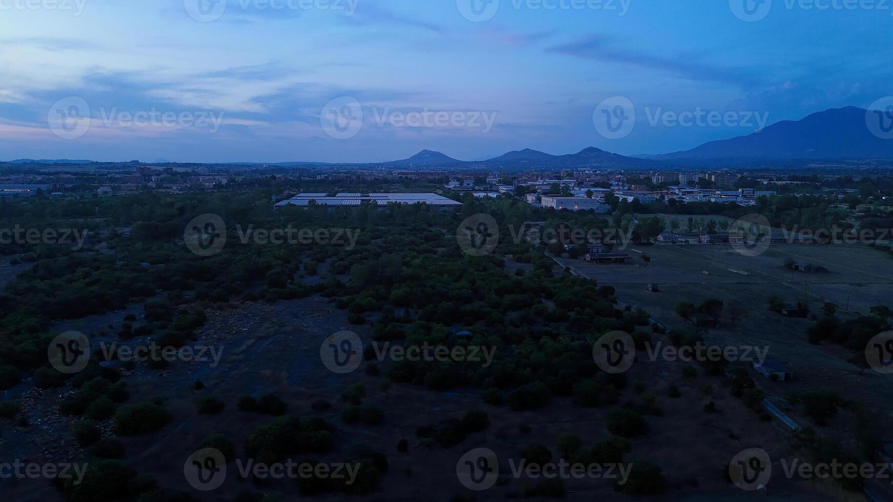 Cityscape turning on lights at dusk with mountains in background photo
