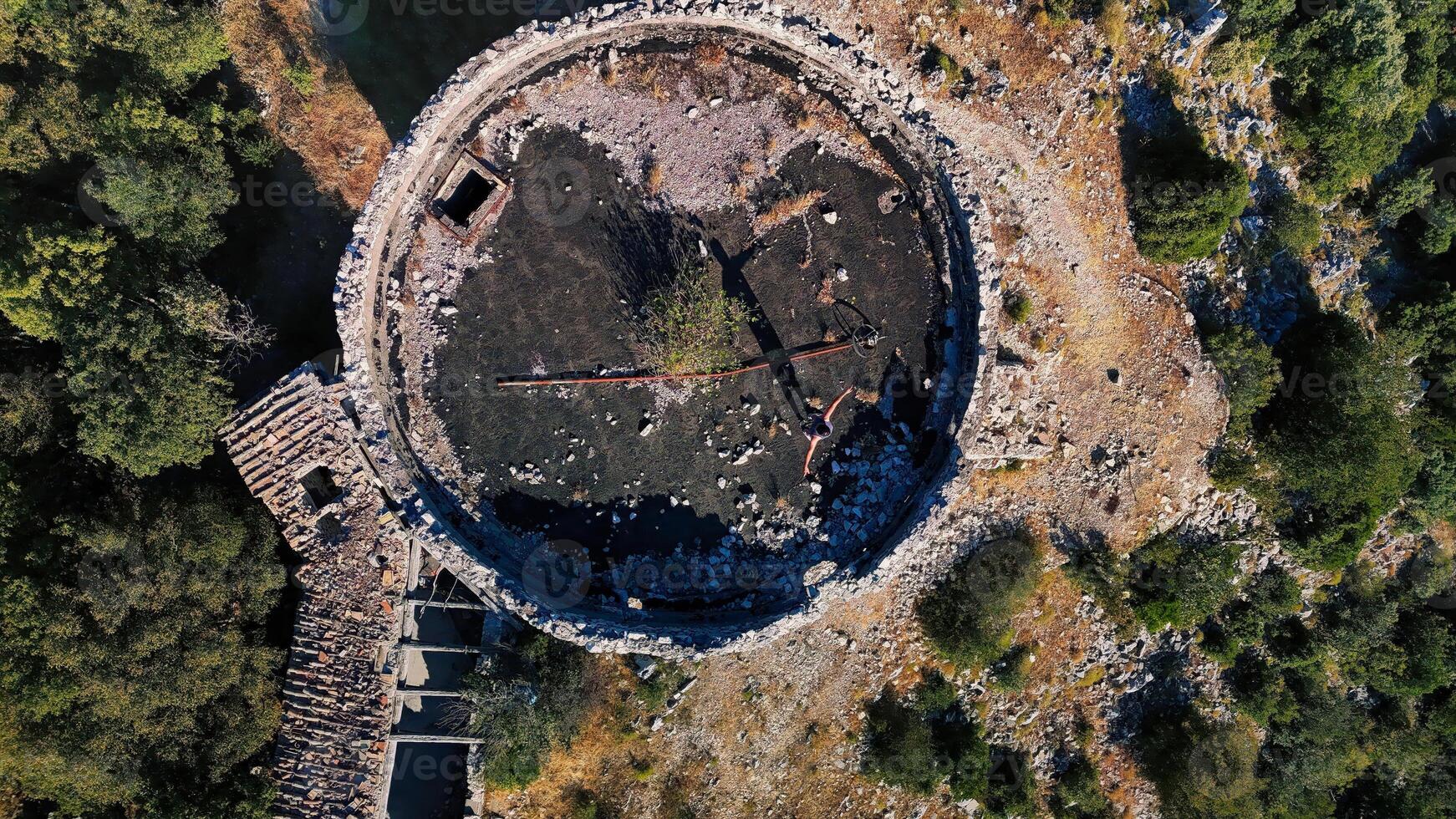 Drone capturing an abandoned ancient tower with a missing roof in the forest photo