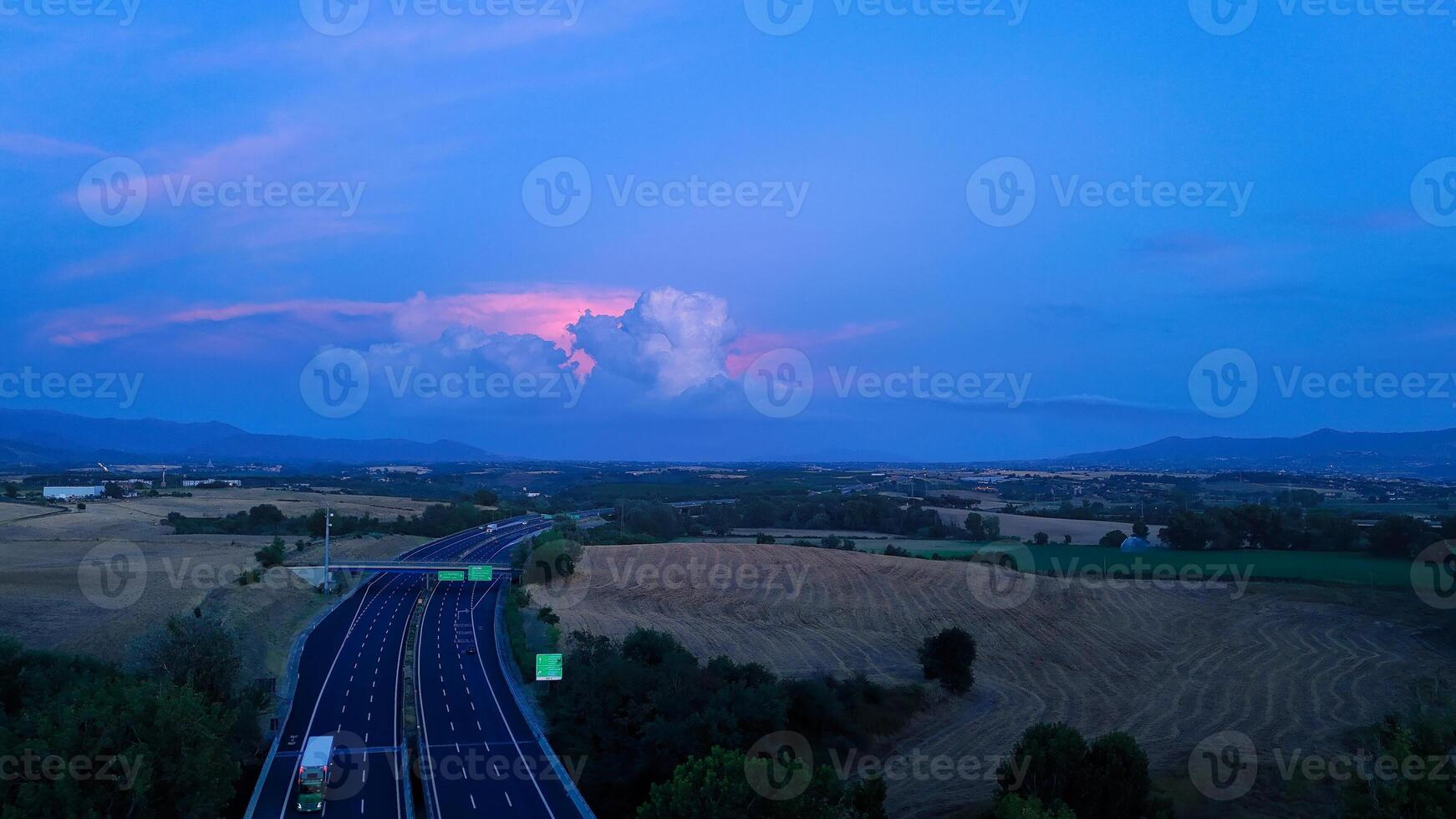 Highway crossing beautiful landscape at dusk with dramatic sky and clouds photo