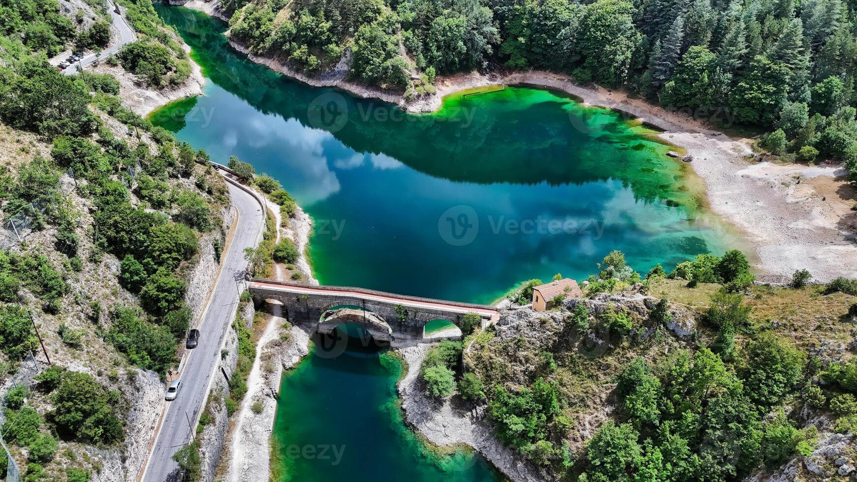 Aerial view of an old bridge connecting two sides of a turquoise lake photo