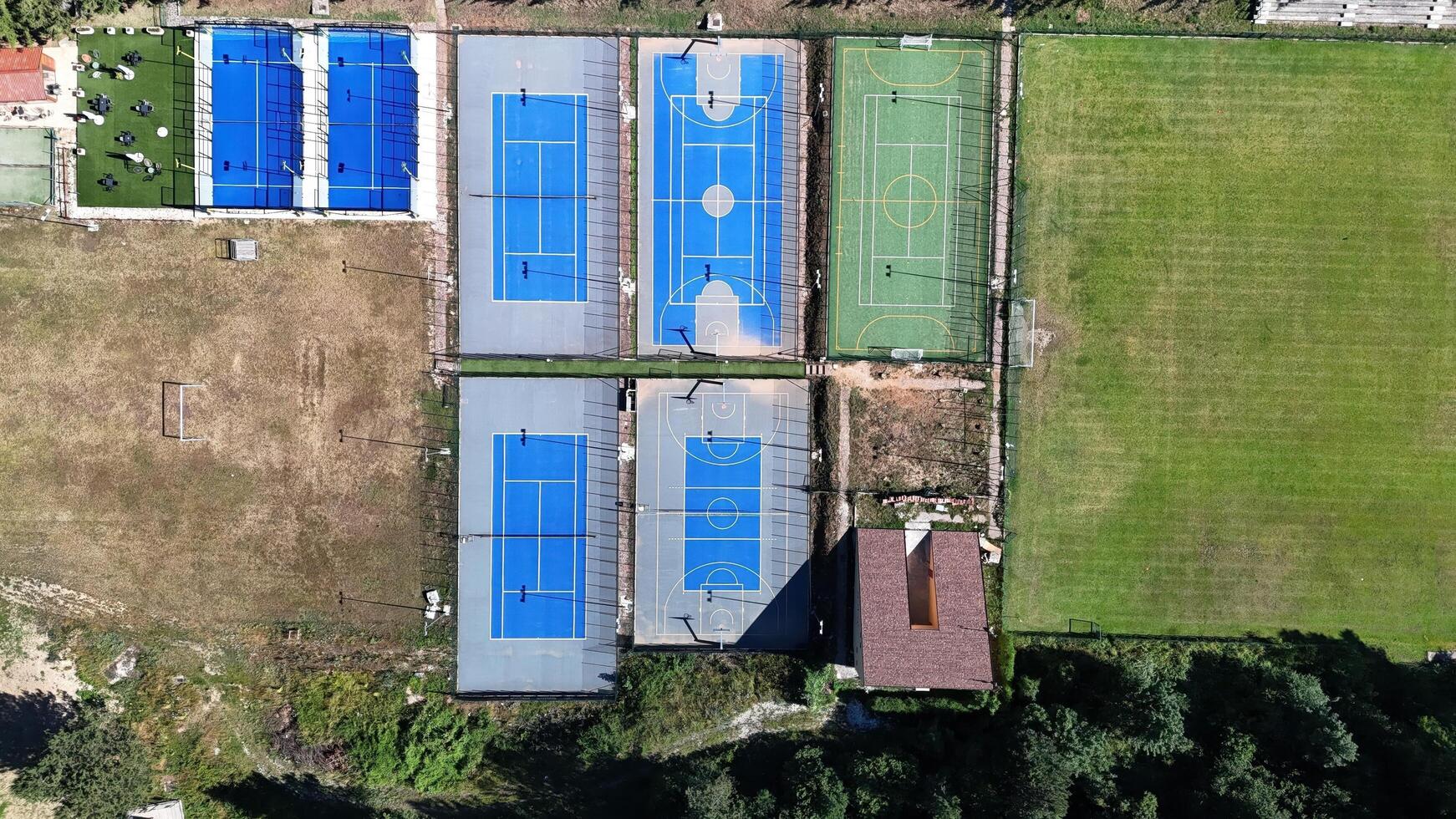 Colorful sports courts and fields captured from above, showcasing vibrant blue tennis and basketball courts alongside green grass fields photo