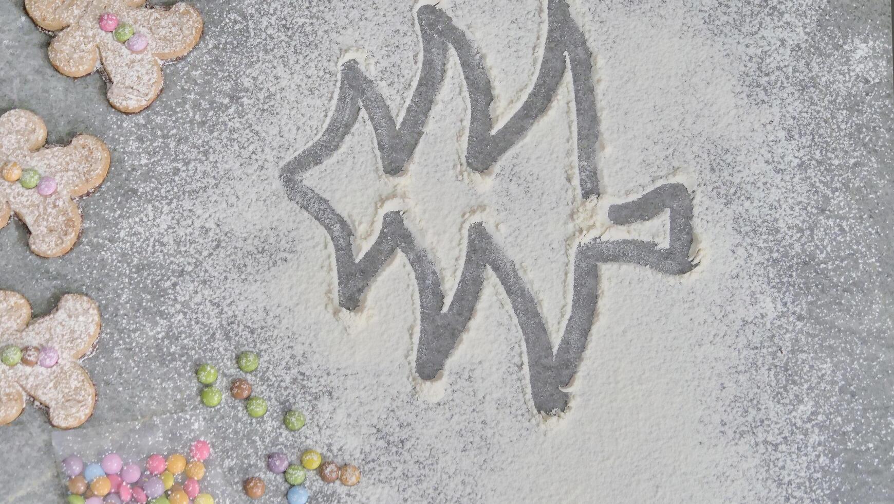 a child's hand draws a Christmas tree in flour photo