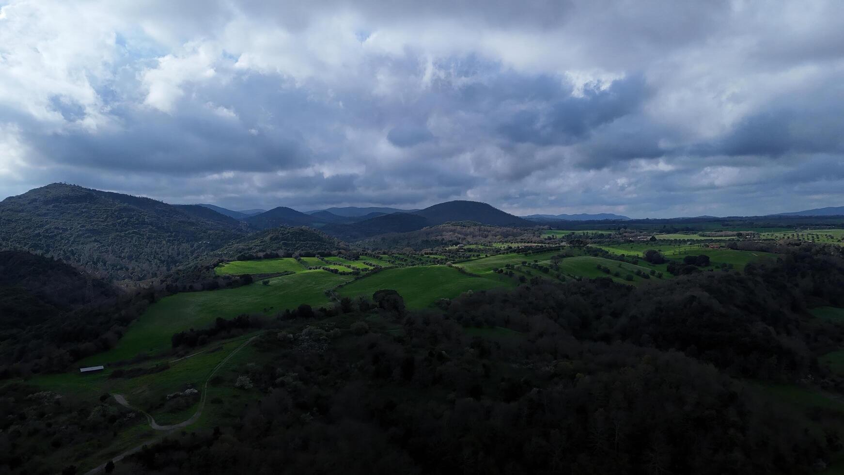 Vast green valleys and rolling hills under a dramatic cloudy sky during late afternoon in a serene countryside landscape photo