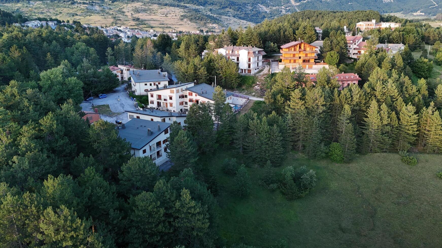 Nestled in nature, wooden chalets dot the hillside under a bright afternoon sun, inviting relaxation and adventure in the mountains photo