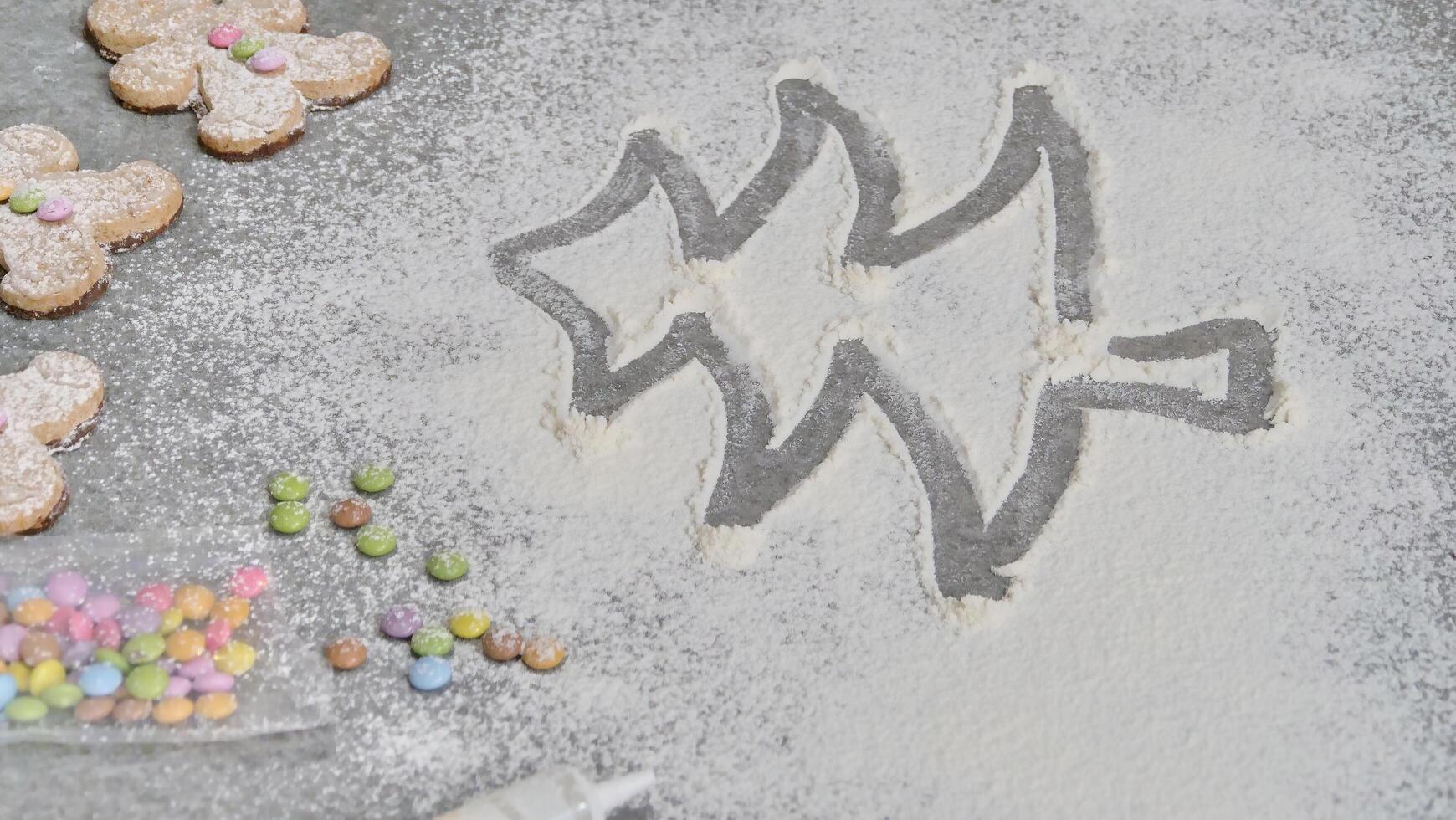 a child's hand draws a Christmas tree in flour photo