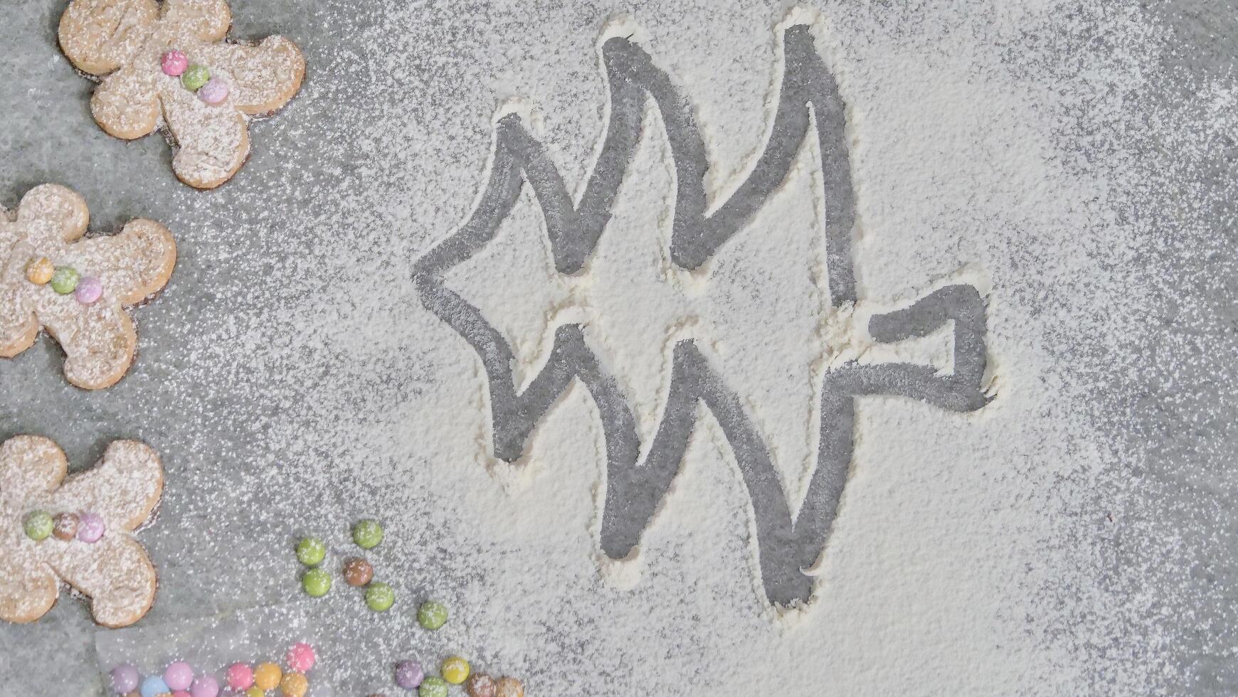 a child's hand draws a Christmas tree in flour photo