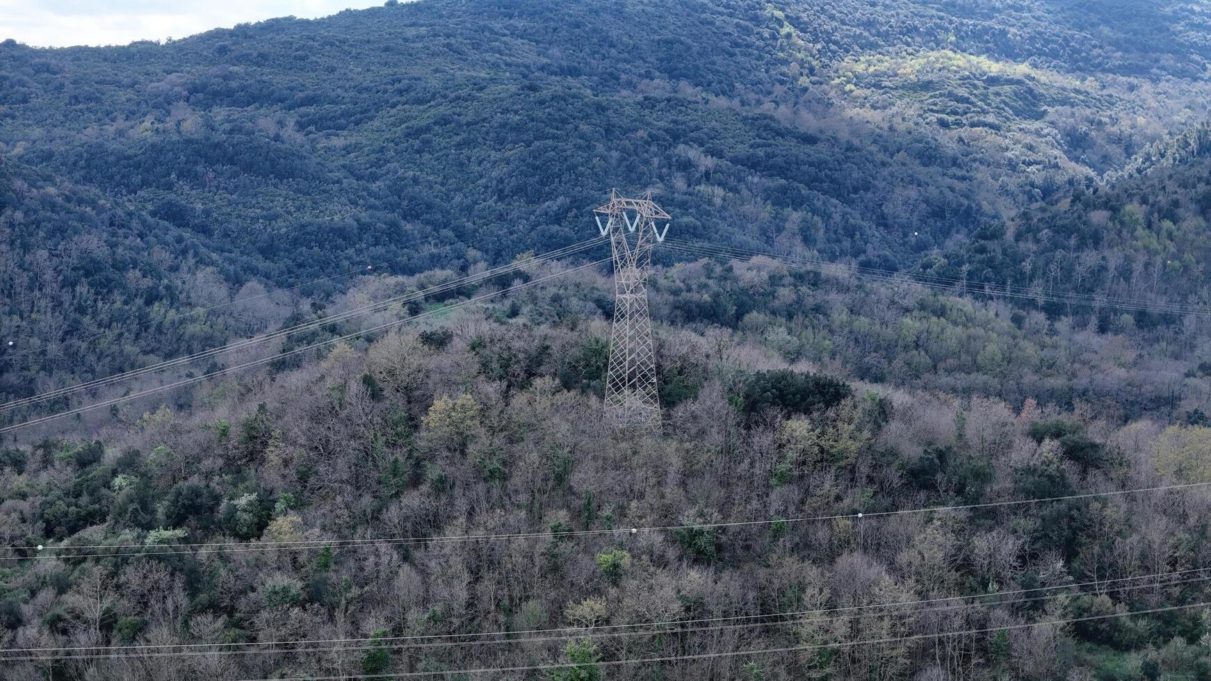 Power lines stretch across a vast mountain landscape, showcasing nature's raw beauty during late afternoon light photo