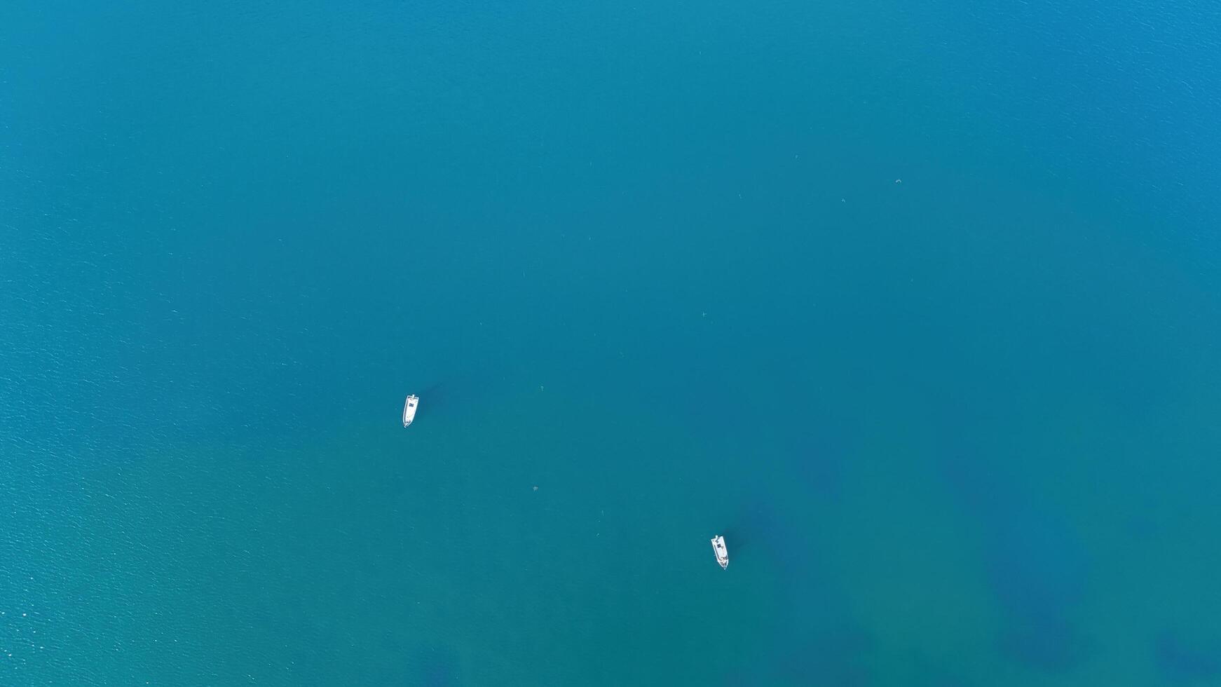 A serene moment on the tranquil blue waters with two boats gliding peacefully under the bright midday sun at a coastal location photo