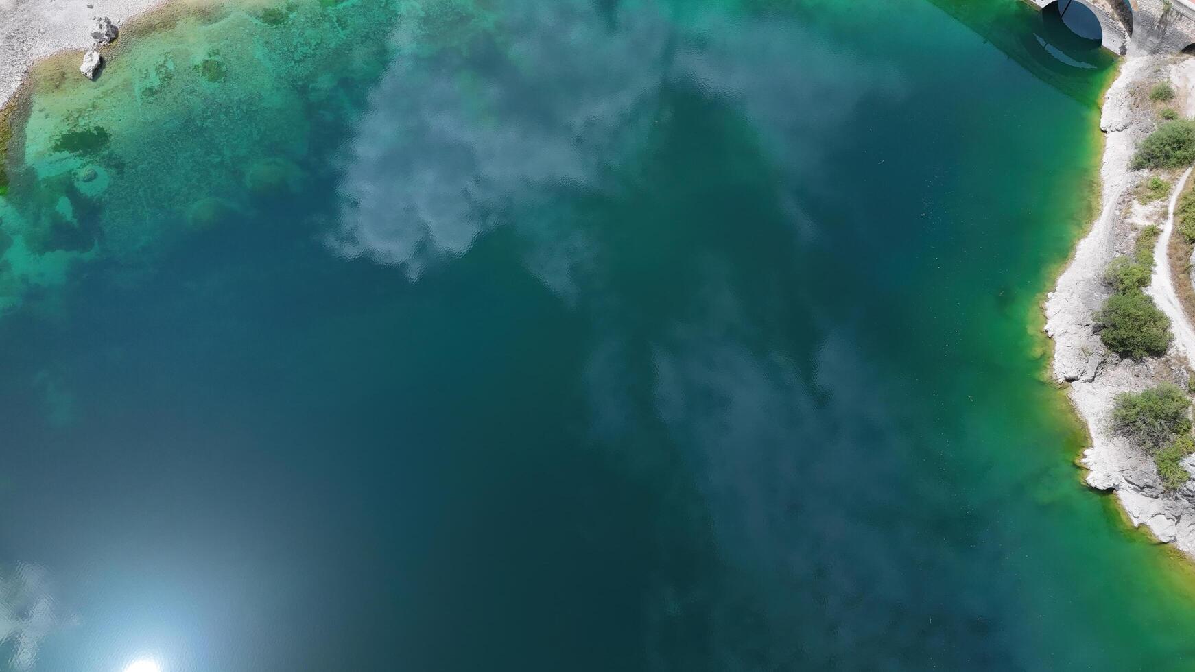 Serene emerald waters reflecting the sky at a hidden lake on a sunny afternoon surrounded by nature's untouched beauty photo